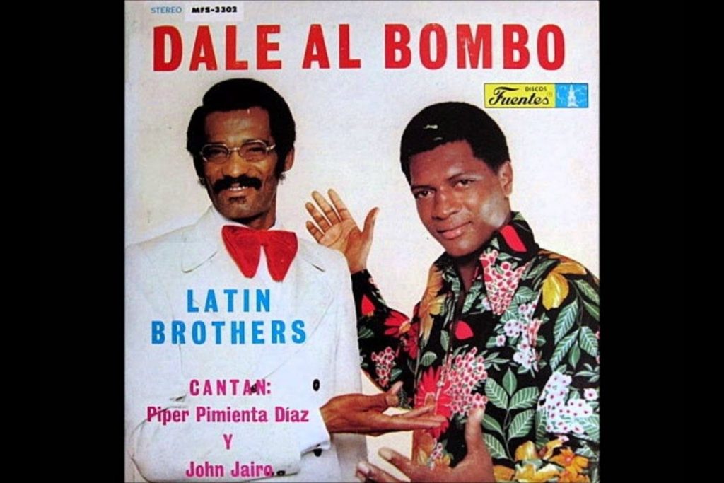 Portada del álbum "Dale al Bombo" de The Latin Brothers, con los icónicos cantantes Piper Pimienta Díaz y John Jairo. Esta carátula representa la época dorada de la salsa de Discos Fuentes, un disco que contiene éxitos inolvidables y que evoca la nostalgia de las fiestas y los bailes de salón que marcaron a la audiencia.