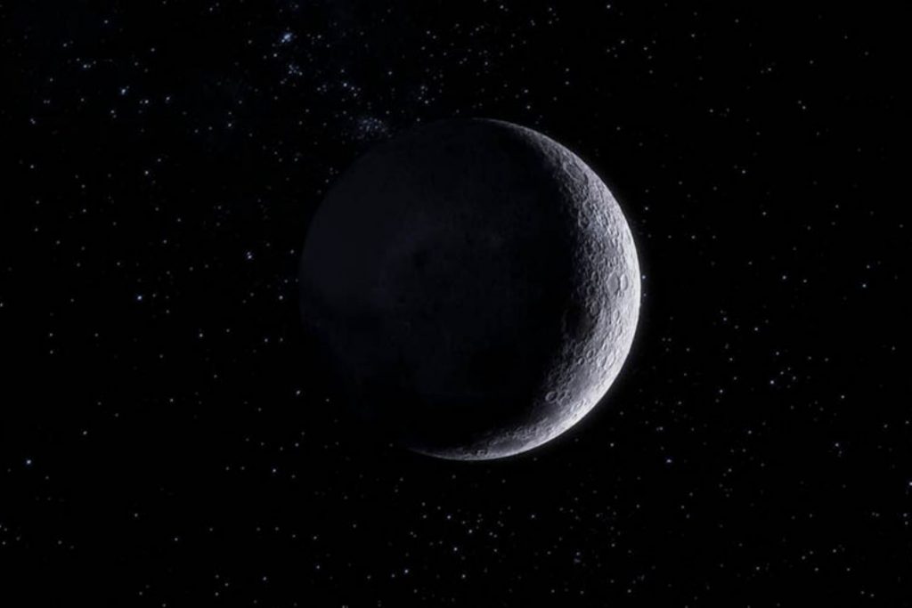 La Luna Negra en su fase de luna nueva vista desde el espacio. La mayor parte del satélite está en oscuridad, con solo un borde iluminado, rodeada por estrellas en el profundo cielo nocturno.