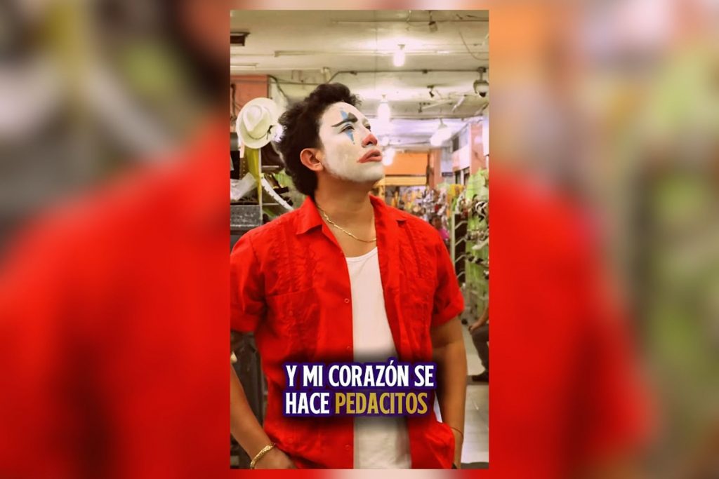 Un hombre con maquillaje de payaso y expresión melancólica en un mercado, con la frase "Y mi corazón se hace pedacitos" del trend "Ojitos Mentirosos", conectando la imagen con la letra de la cumbia viral.