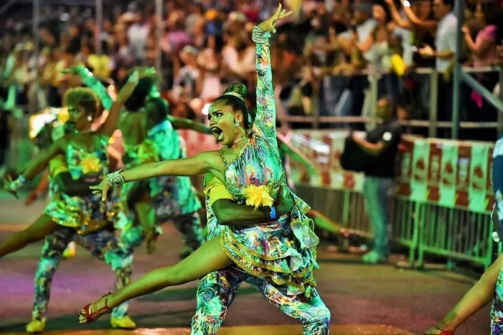  Una pareja de bailarines de salsa realizando una acrobacia durante un desfile nocturno.