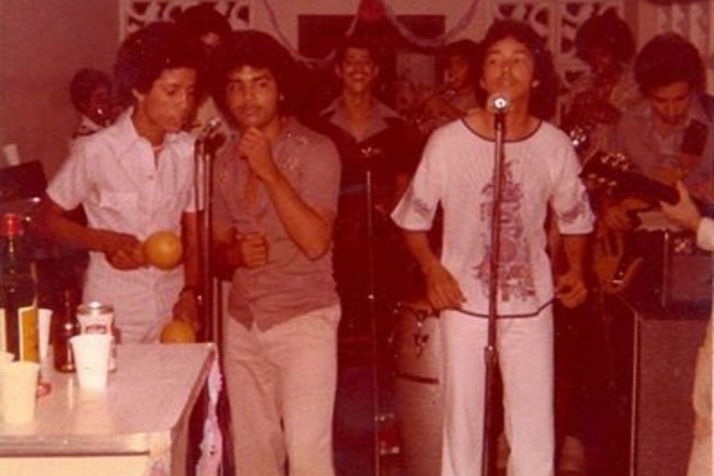 Una foto antigua de Gilberto Santa Rosa cantando con su orquesta en sus inicios. La nota celebra la larga y exitosa trayectoria del "Caballero de la Salsa".
