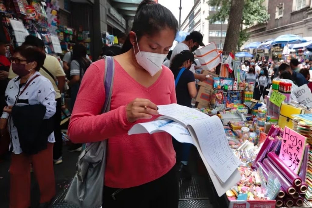 Una madre de familia revisando la lista de útiles escolares antes de comprar. La nota da recomendaciones de Profeco para no gastar de más en el regreso a clases.