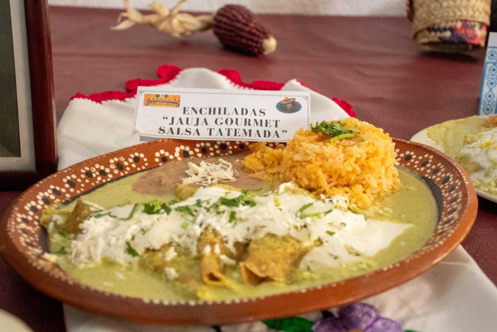 Un plato de enchiladas servido en un puesto de la feria. La nota destaca el ambiente familiar y la comida tradicional de la Feria de la Enchilada.