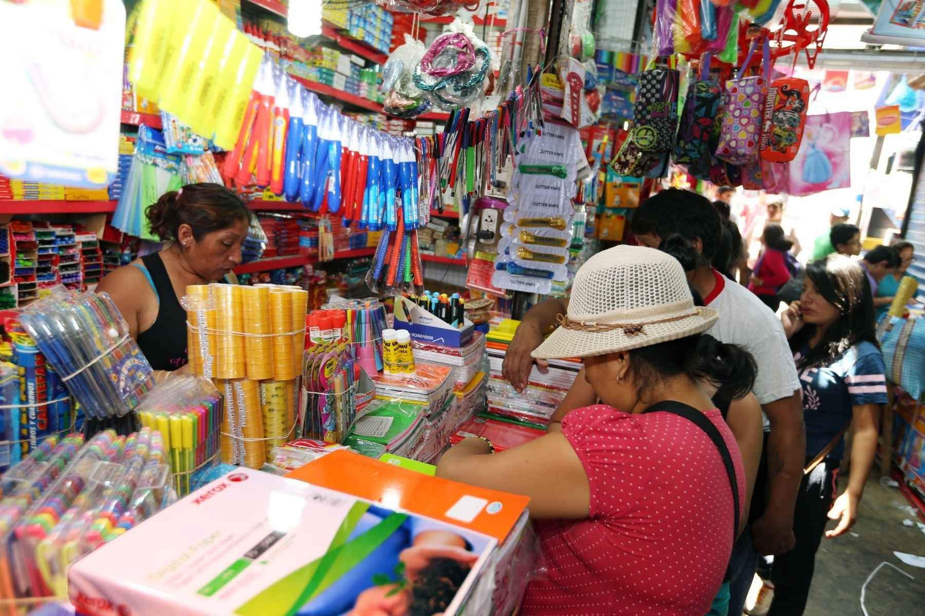 Un grupo de personas comprando en un puesto de útiles escolares.