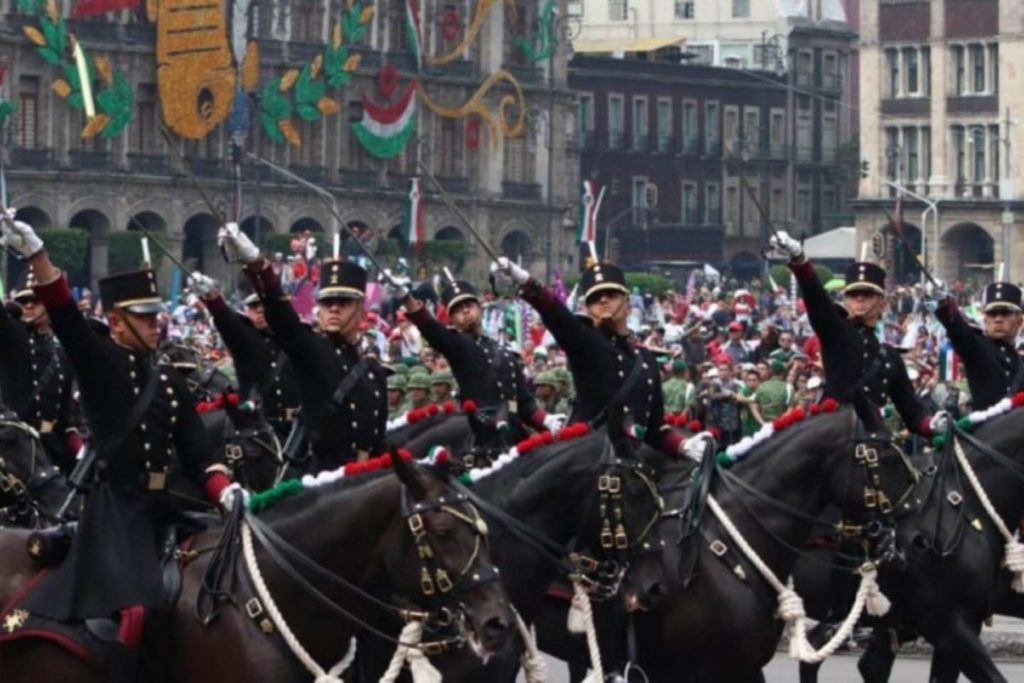 El contingente de la caballería del Ejército Mexicano con sables en alto durante el desfile. La nota celebra la gallardía y la historia de las Fuerzas Armadas.