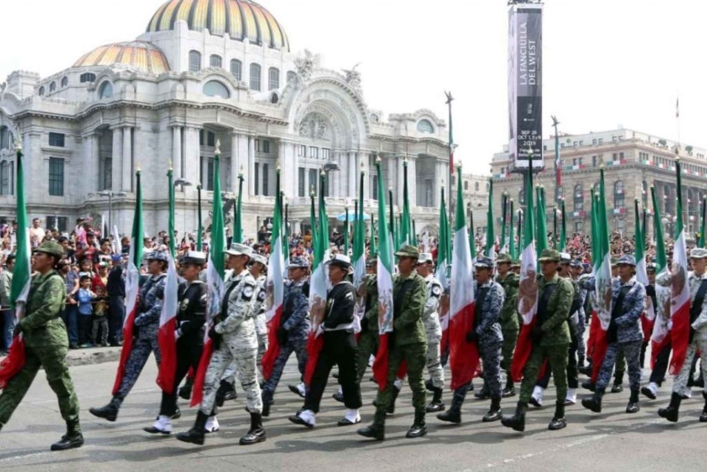 Un contingente de la Guardia Nacional y el Ejército marchando frente al Palacio de Bellas Artes. La nota explica el significado del Desfile Militar del 16 de Septiembre.