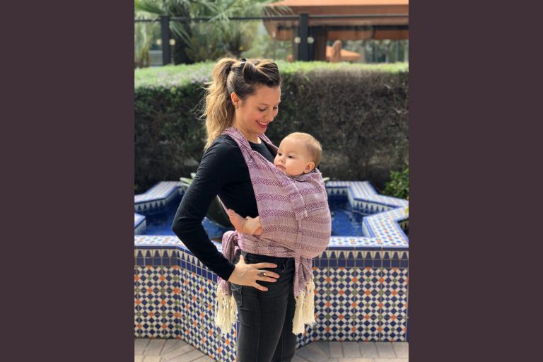Mujer cargando a bebe con un rebozo, la nota habla de las diferentes maneras que hay de usar un rebozo