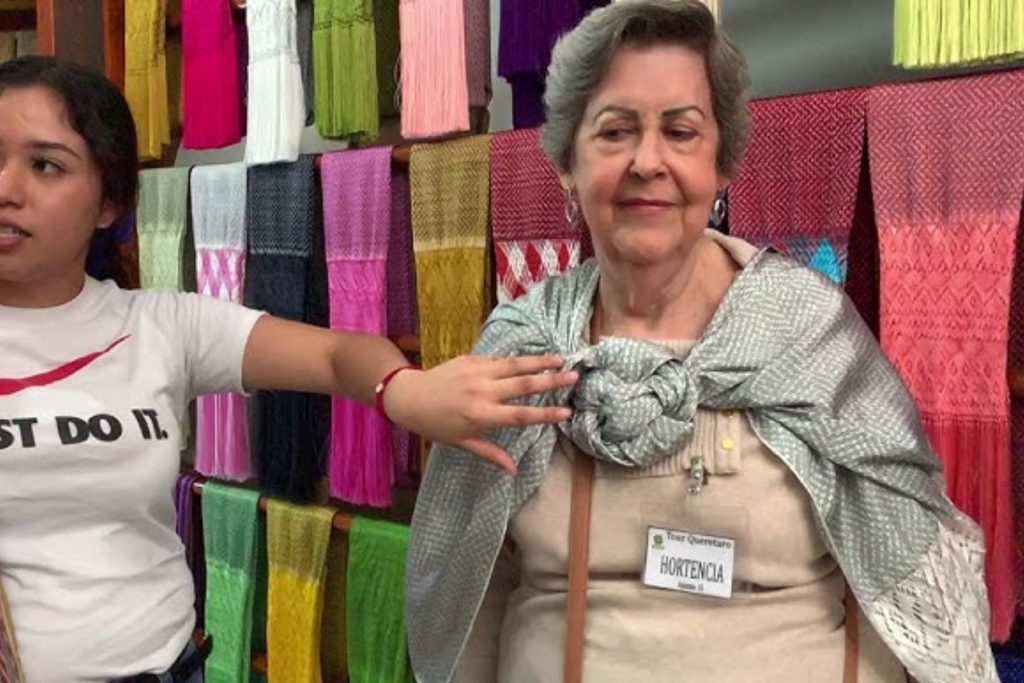 Una mujer mostrando cómo anudar un rebozo para darle un toque sofisticado. El artículo da consejos de estilo para usar esta prenda en cualquier ocasión.
