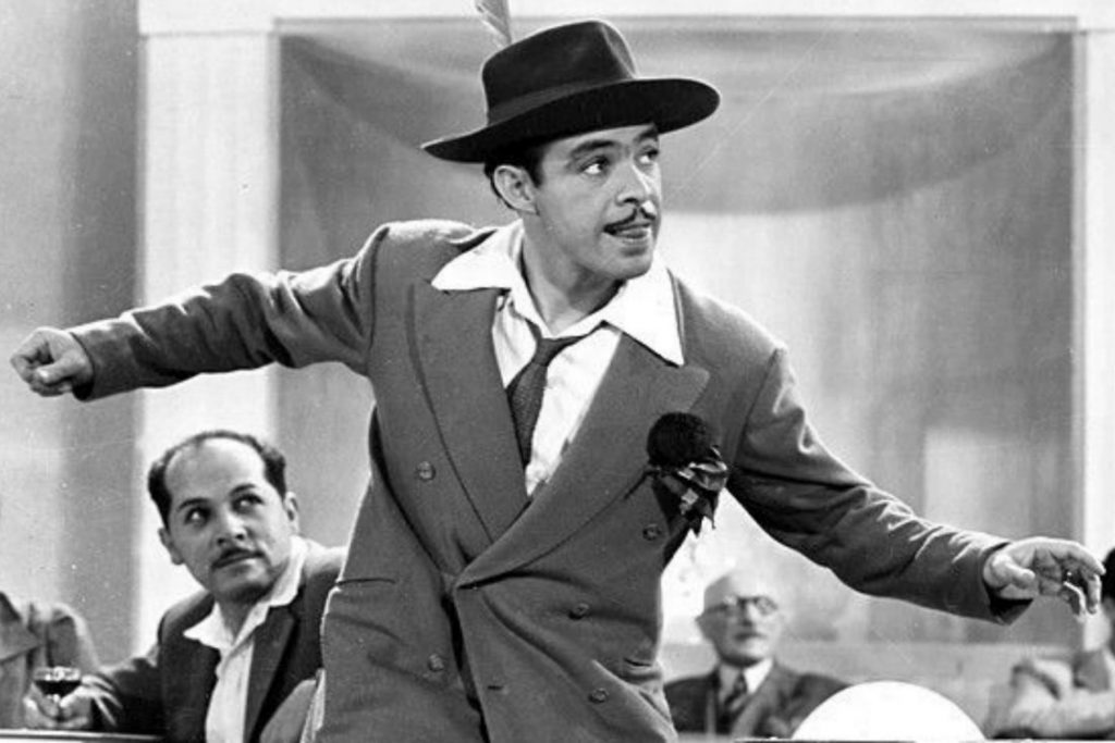 El actor Germán Valdés "Tin Tan" bailando en una escena de sus películas, vestido como el Pachuco de Oro. La nota celebra su vida y carrera.