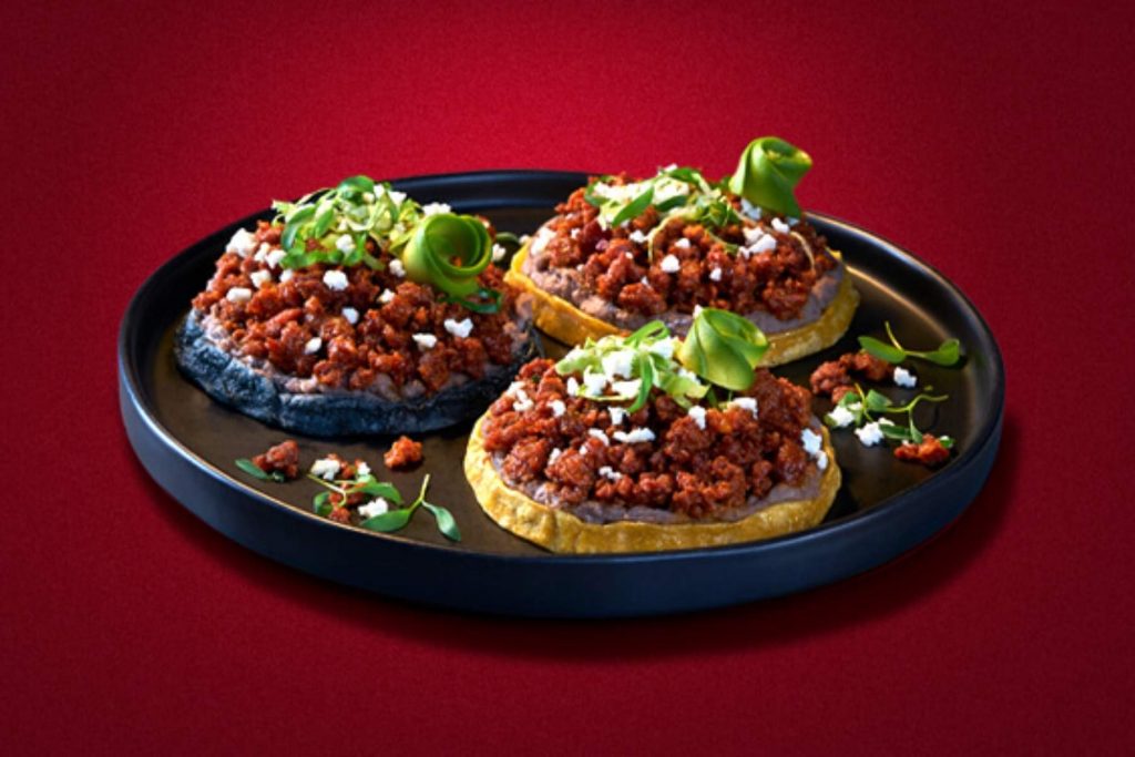 Tres sopes con frijoles, chorizo y queso fresco, listos para la fiesta. La nota comparte recetas de antojitos mexicanos fáciles de preparar en casa.