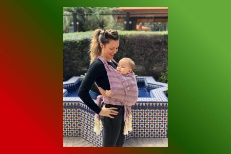 Una mamá cargando a su bebé de forma segura y cómoda con un rebozo. La nota destaca el uso tradicional del rebozo como portabebés y sus beneficios para la crianza.