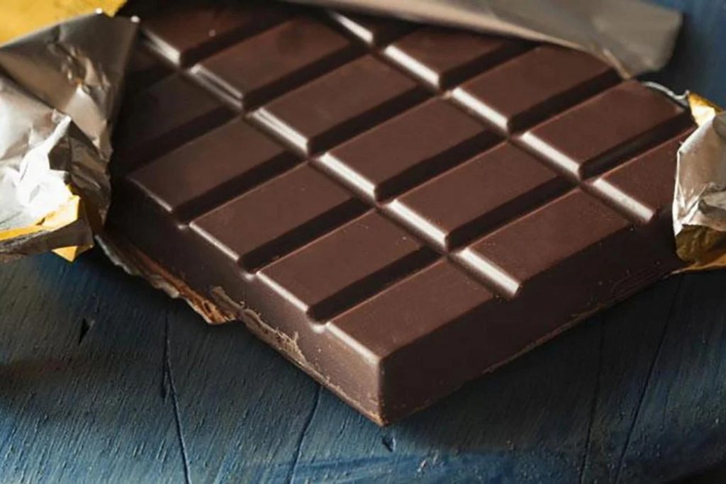 Una barra de chocolate oscuro semi-desenvuelta. La nota explica la diferencia entre los tipos de chocolate y cómo elegir el de mejor calidad.