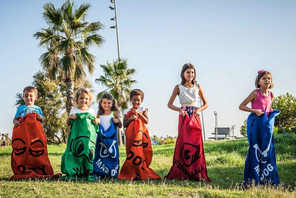 Un grupo de niños listos para empezar una carrera de sacos. La nota da ideas de juegos al aire libre para organizar en la fiesta del 15 de septiembre.