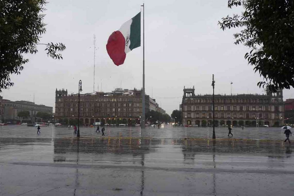 El Zócalo de la Ciudad de México en un día lluvioso. La nota informa sobre el pronóstico del clima para la celebración del Grito de Independencia el 15 de septiembre.