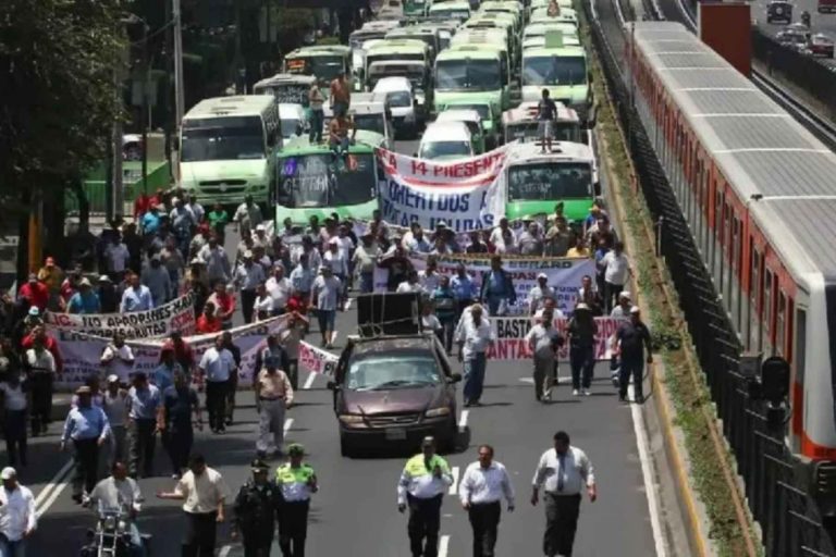 Una manifestación de transportistas bloqueando una avenida principal en la CDMX. La nota informa que la megamarcha planeada para este lunes fue suspendida.