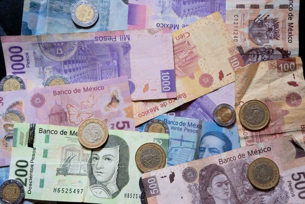 Billetes y monedas de pesos mexicanos de diferentes denominaciones. La nota informa sobre la demanda de aumento a la tarifa por parte de los transportistas.