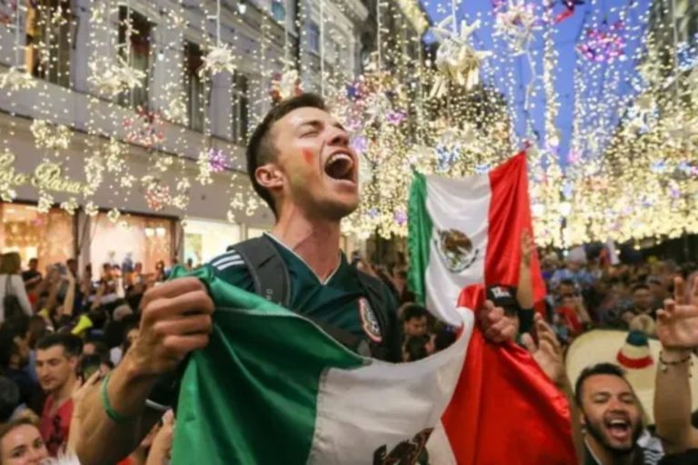 Un aficionado mexicano celebra con pasión y una bandera de México. La nota habla sobre el orgullo y la emoción que nos une durante las Fiestas Patrias.