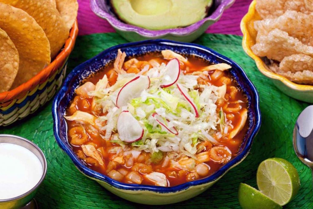 Un plato de pozole rojo estilo Jalisco, servido con lechuga, rábano y tostadas. La nota te enseña la receta de la abuela para que te quede espectacular.